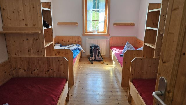 Einfaches Vierbettzimmer in der Tutzinger Hütte mit Holzbetten und Rucksack