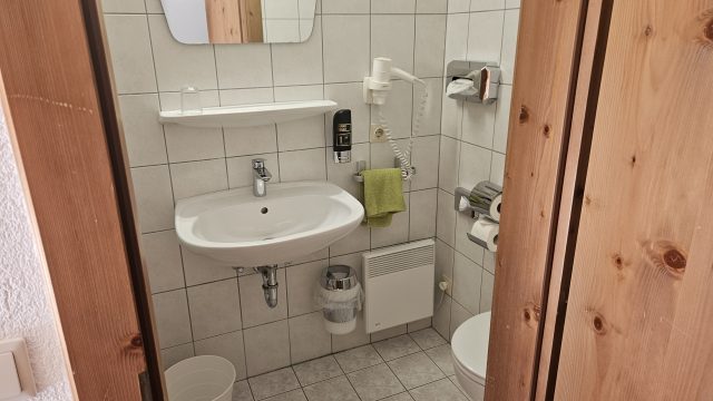 Badezimmer mit Dusche und Haartrockner im Gasthof zur Post Hinterriss