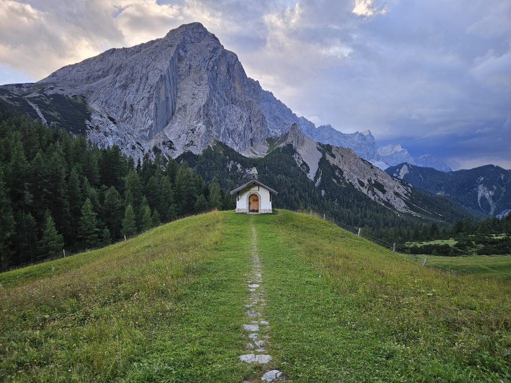Kleine Bergkapelle auf einer Wiese vor der beeindruckenden Lafatscher Nordwand bei der Hallerangeralm
