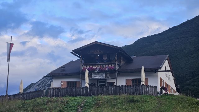 Hallerangeralm mit Holzterrasse und Sonnenschirmen, gelegen auf einer kleinen Anhöhe im Karwendel