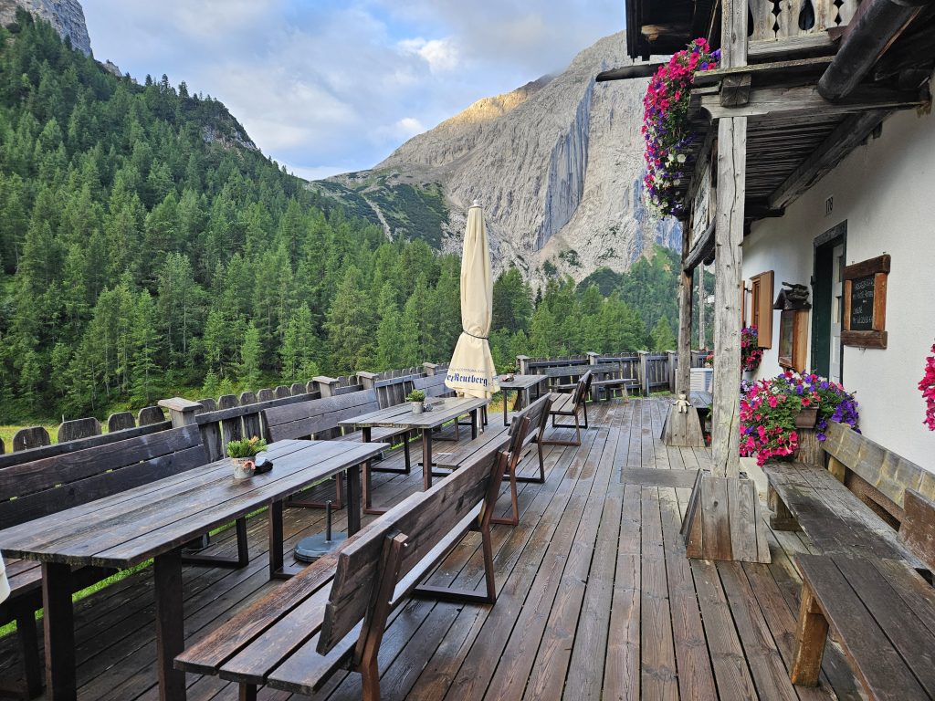 Holzterrasse der Hallerangeralm mit Sitzbänken, Blumen und Blick auf die Lafatscher Nordwand