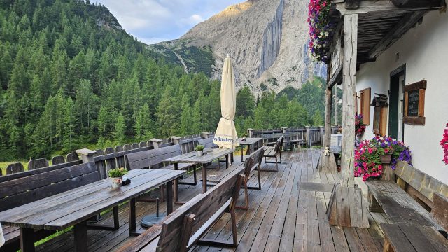 Holzterrasse der Hallerangeralm mit Sitzbänken, Blumen und Blick auf die Lafatscher Nordwand