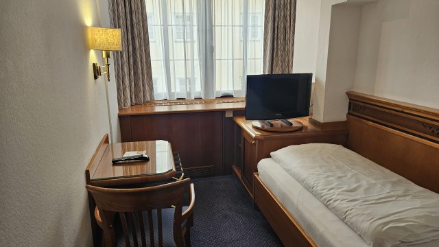 Einfaches Einzelzimmer im Hotel Mondschein mit Schreibtisch, Fernseher und großem Fenster