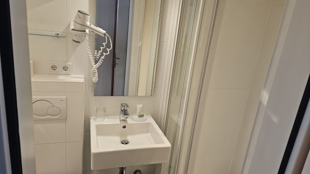 Kompaktes, modernes Bad mit Dusche, Waschbecken, WC und Föhn im Hotel Mondschein