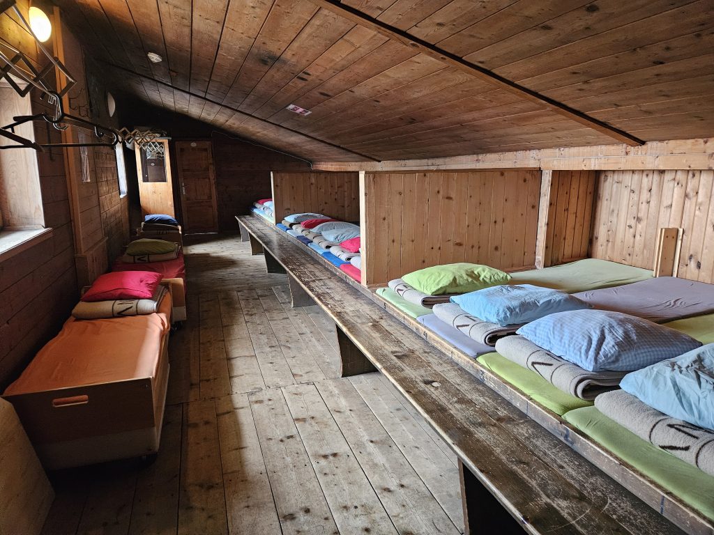 Matratzenlager mit Holzverkleidung und bunten Decken in der Glungezerhütte