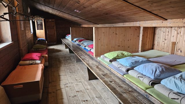 Matratzenlager mit Holzverkleidung und bunten Decken in der Glungezerhütte