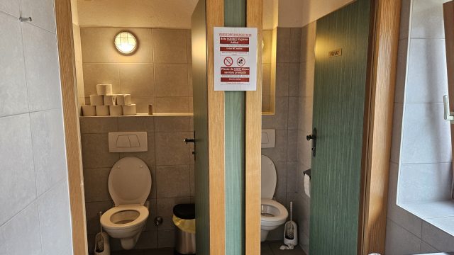 Zwei offene Toilettenkabinen in einem gefliesten Waschraum