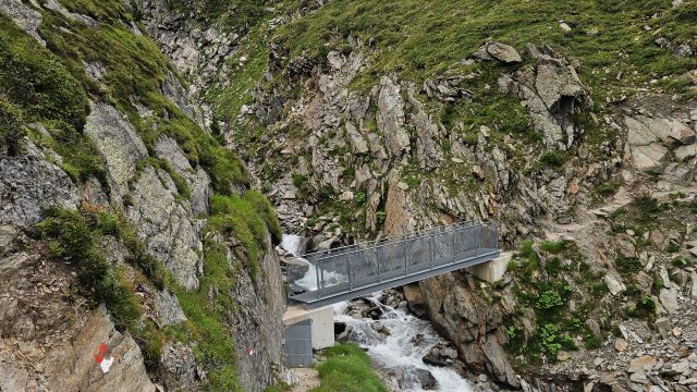 Wanderweg mit Brücke über Gebirgsbach in alpiner Landschaft nahe der Geraer Hütte in Tirol.