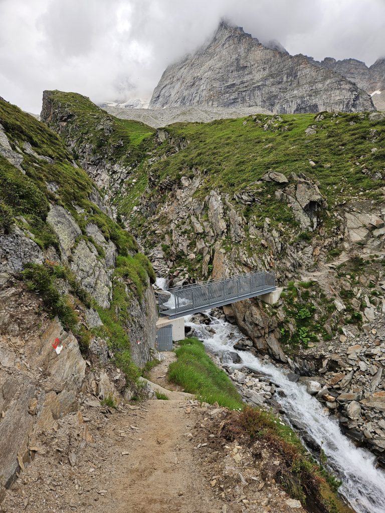 Wanderweg mit Brücke über Gebirgsbach in alpiner Landschaft nahe der Geraer Hütte in Tirol.