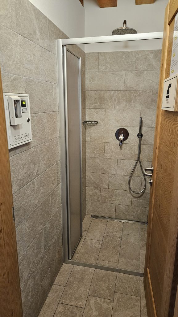 Dusche mit Fliesen und Duschkopf in Rifugio Boè