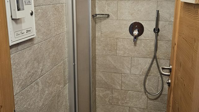 Dusche mit Fliesen und Duschkopf in Rifugio Boè