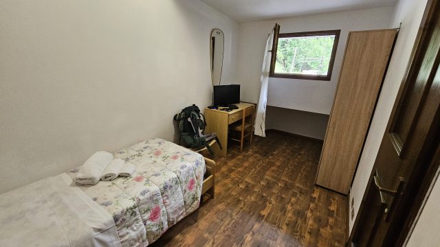 Einfach eingerichtetes Einzelzimmer mit Holzfußboden im Hotel Tea Dolomiti