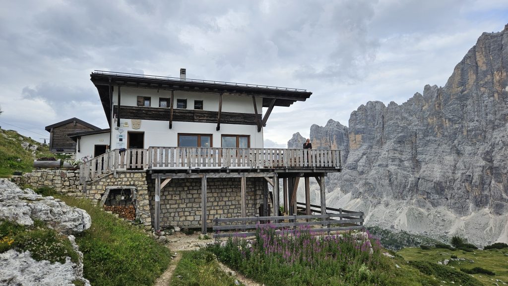 Rifugio Tissi mit Holzterrasse vor dramatischer Felswand