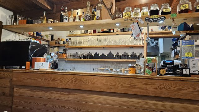 Bar im Rifugio Cesare Tomè mit Gläsern, Flaschen und Deko.