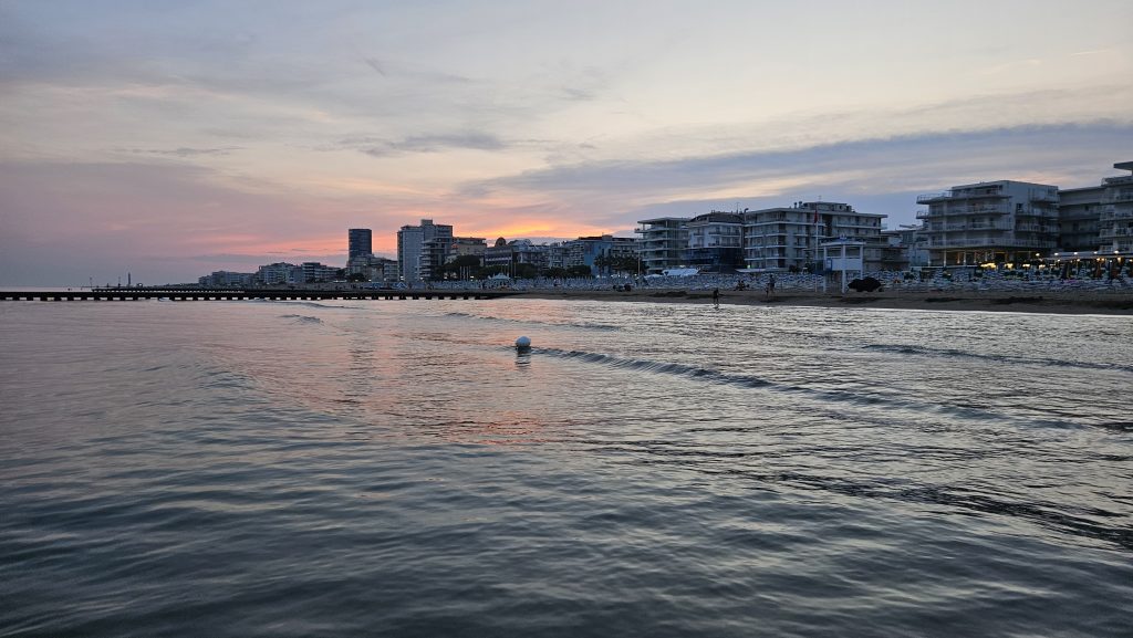 Blick vom Wasser auf den beleuchteten Strand von Jesolo im Sonnenuntergang