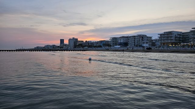 Blick vom Wasser auf den beleuchteten Strand von Jesolo im Sonnenuntergang