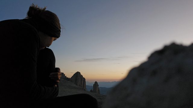 Person im Morgengrauen mit Blick auf Dolomitengipfel
